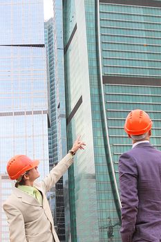 Two businessmen in business suits and helmets on building