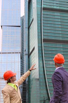 Two businessmen in business suits and helmets on building