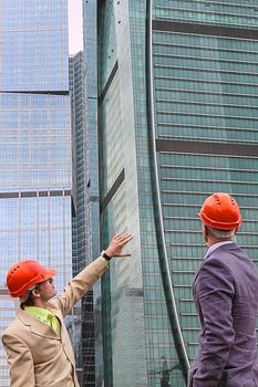 Two businessmen in business suits and helmets on building