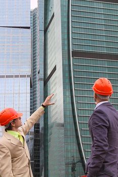 Two businessmen in business suits and helmets on building