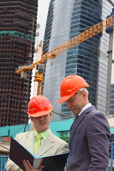 Two businessmen in business suits and helmets on building
