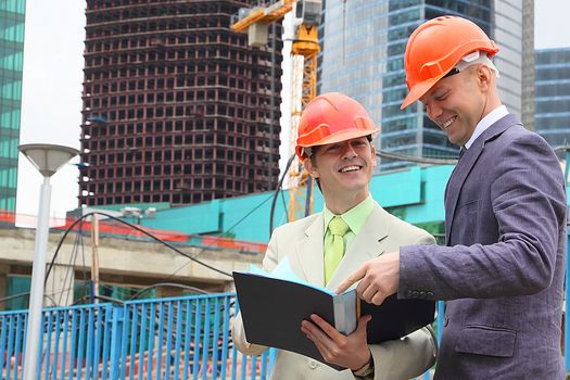 Two businessmen in business suits and helmets on building