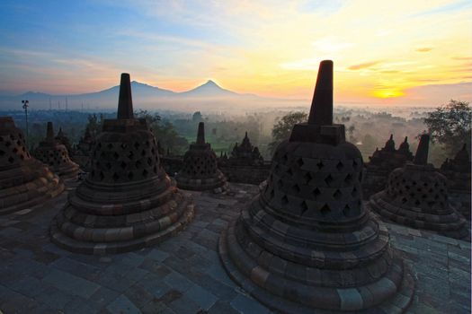 Sunrise at Ancient stupa Borobudur Temple, with Mount Merapi Background in Yogyakarta, Java, Indonesia.