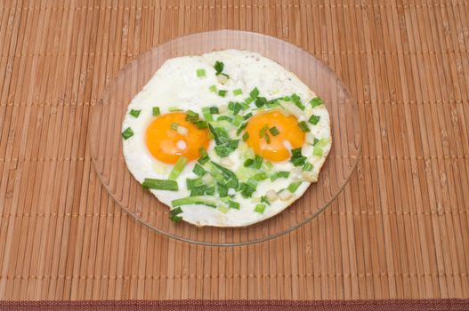 Fried eggs with green onions on a bamboo mat.