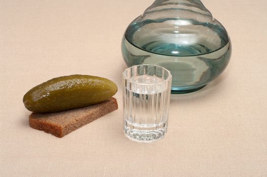 Wineglass of vodka pickles and rye bread close up.