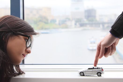 The finger of the businessman moves the toy car