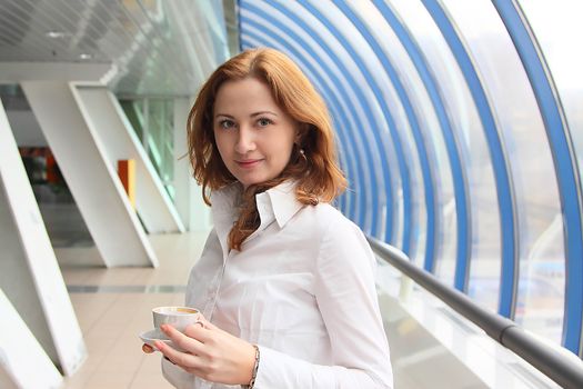 The businessman drinks coffee at office from a small white cup