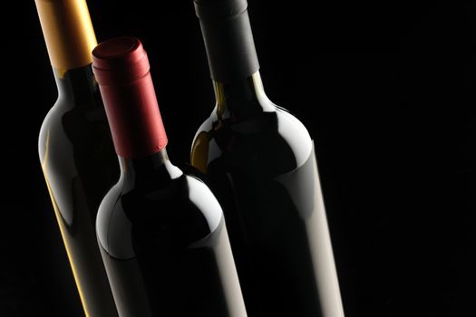 bottles of red and white wine on black background