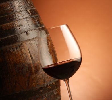 red wine glass and woodden barrel at background