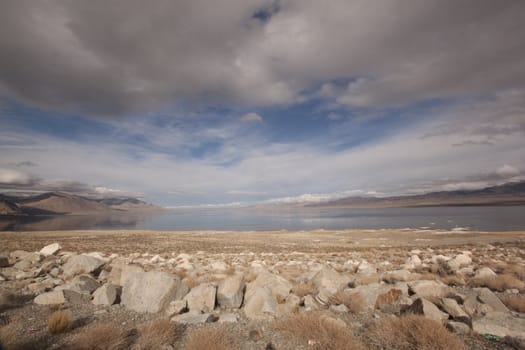 A lonely highway by a desert mountain range and lake