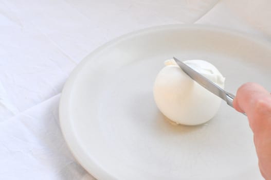 Cook hand cutting traditional Italian mozzarella di bufala (buffalo mozzarella) cheese made from buffalo milk