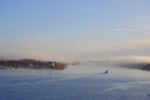 A small ship leaves Stockholm a misty morning.