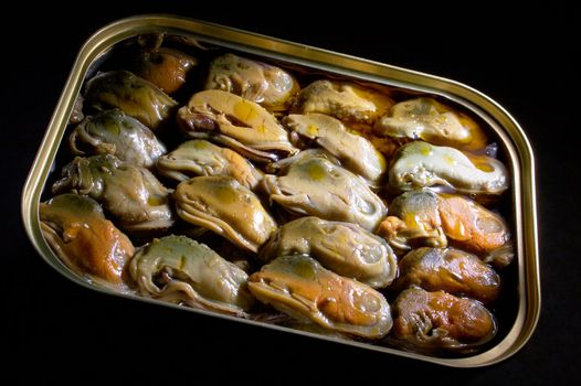 Smoked mussels in vegetable oil on a black background