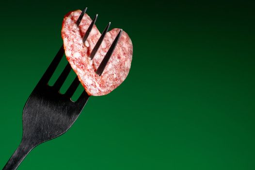 Sausage in the form of heart on a green background