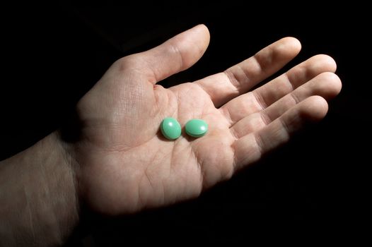 Two green tablets on the opened palm