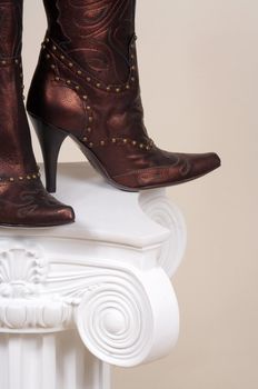 Leather female boots on a white podium