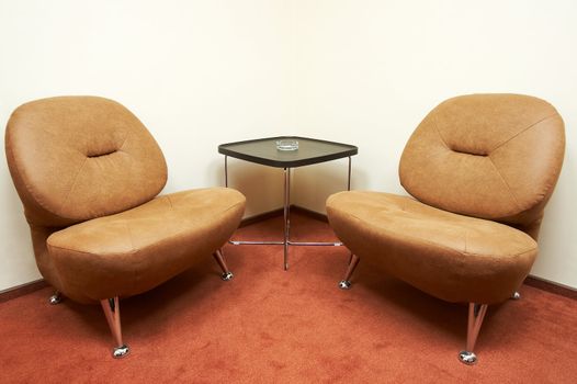 Two leather armchairs and ashtray on a table