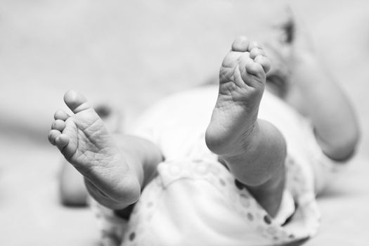 Newborn happy cute baby feet with toes and wrinkles. Infant child laying on back.