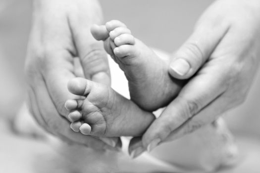 Mother's gentle touch holding cute baby feet.