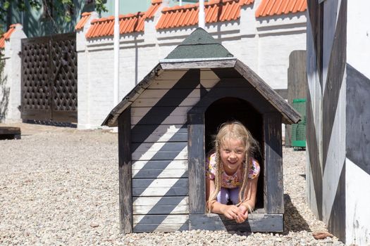 smiling little girl in old wooden dog house