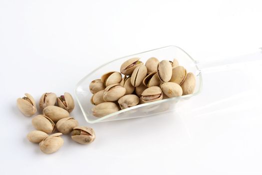 a scoop of roasted and salted pistachio nuts on white background