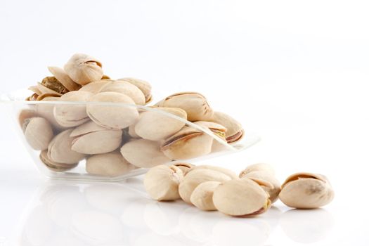 a scoop of roasted and salted pistachio nuts on white background