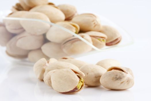 a scoop of roasted and salted pistachio nuts on white background