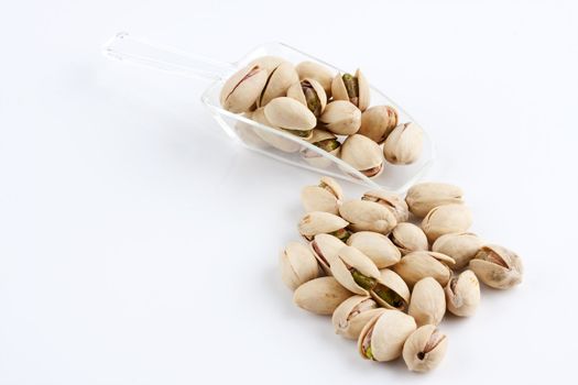 a scoop of roasted and salted pistachio nuts on white background