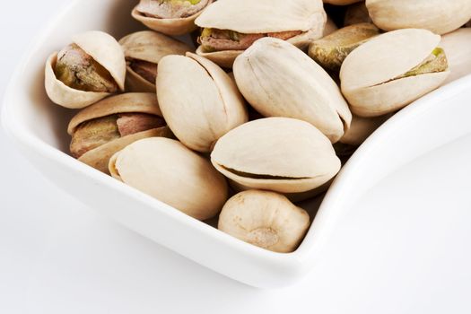 Close-up roasted and salted pistachios on white plate