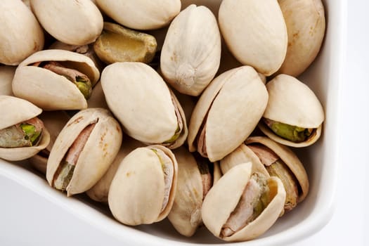 Close-up roasted and salted pistachios on white plate