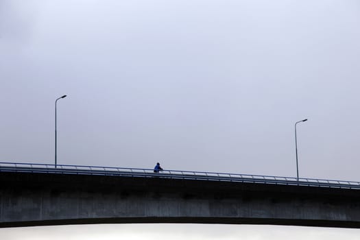 cyclist on bridge and threatening sky