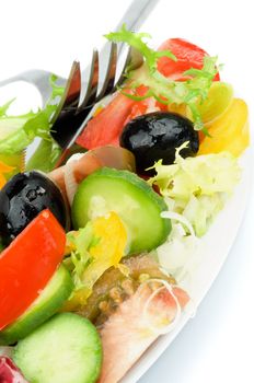 Vegetable Salad with Tomatoes, Yellow Bell Pepper, Leek, Cucumber, Lettuce, Olive Oil and Black Olive on White Plate with Fork and Knife closeup on White background