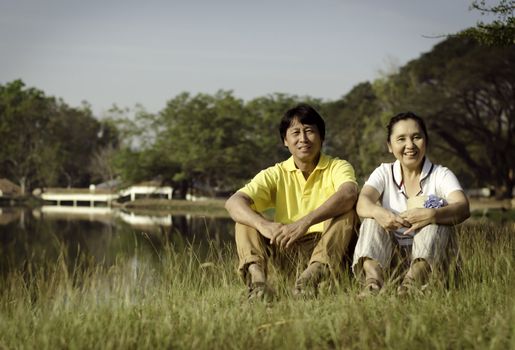 Portrait of beautiful couple sitting on ground in park relaxing 