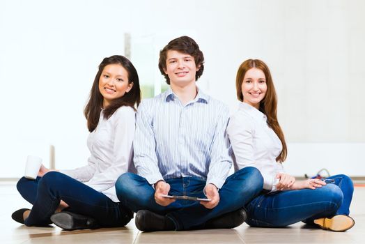 portrait of a group of young people sitting on the floor, man and two attractive women