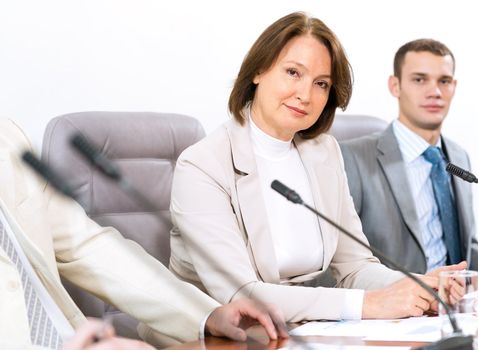 Portrait of a senior business woman at the meeting, sitting at a table on which are microphones