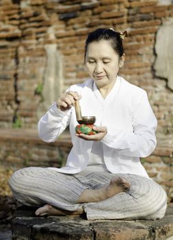 Asian woman playing a tibetan bowl, traditionally used to aid meditation in Buddhist cultures. 