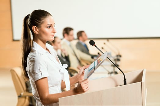 Portrait of a business woman holding a microphone and looks ahead