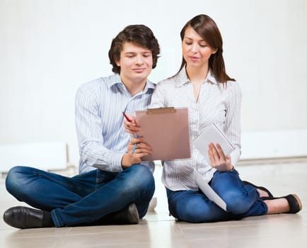 Attractive young man and woman sitting on the floor talking