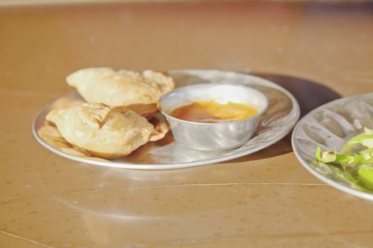 Shot taken at a Dhabha in Alung Gujarat India. Breakfast of samosas, chilli dip and stir fried white cabage with fresh green chillies