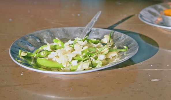 Shot taken on the outskirts of Alung in Gujarat, India at a greasy spoon breakfast bar. Dust, dirt and damaged tables with a serving of stir fried white cabbage in a steel plate.