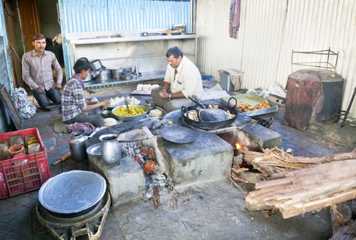 Alung, Gujarat, India - February 26, 2013: Shot location was the kitchen and staff at greasy cafe dhabha at Alung, Gujarat India. The chef and porters are making and cooking fresh samosas while the wood burning stoves are used for frying.