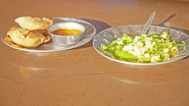 Shot taken at a Dhabha in Alunga Gujarat India. Breafast of samosas, chilli dip and stir fried white cabage with fresh green chillies