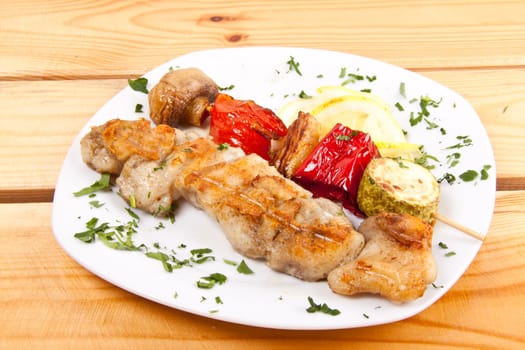 grilled meat pieces on wood sticks with vegetables