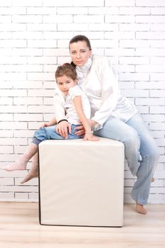 Mom and daughter in the same clothes sitting on the cube