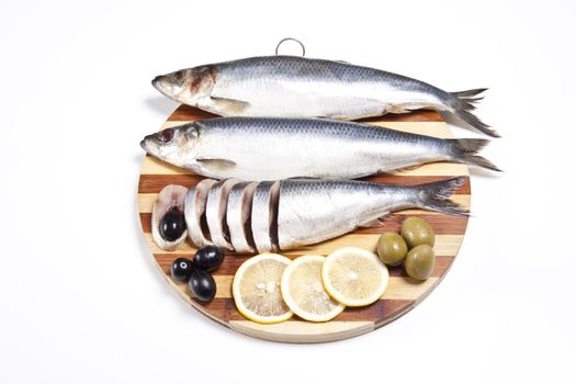 Fish with lemon and olive on wooden plate