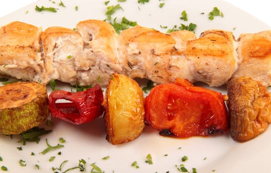 grilled meat pieces on wood sticks with vegetables close up