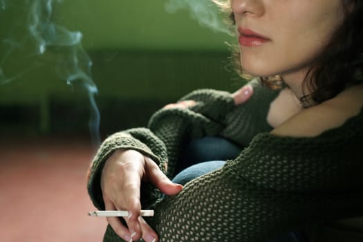 Portrait of the girl with a cigarette on a green background