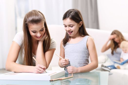 Two girls write something for a glass table