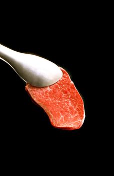 piece of meat on a fork isolated on black background