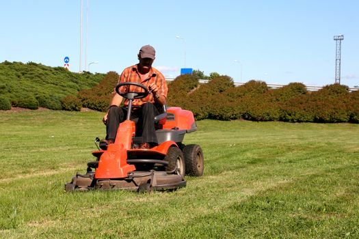 Mature man driving grass cutter in a sunny day